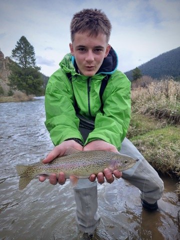 Roán holding a trout while fly fishing